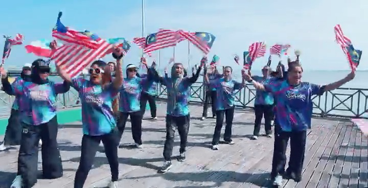 Peserta membawa Jalur Gemilang di tepi laut